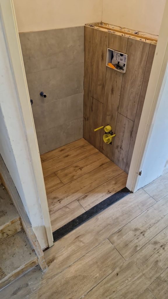 Installatie houten vloertegels en wand in kleine badkamer