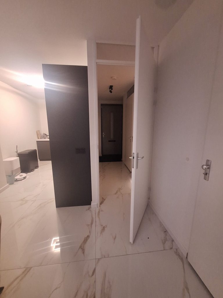 Moderne hal met geopende deur en marmeren vloer.