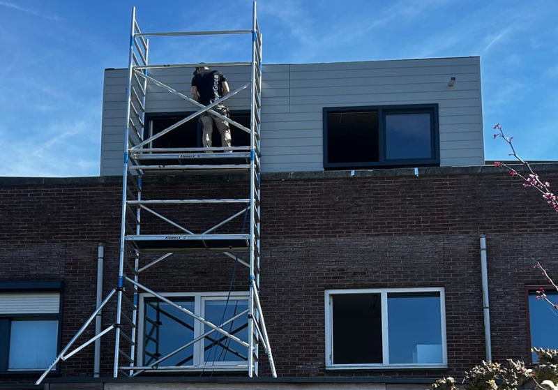 Bouwvakker op steiger werkt aan gevel.