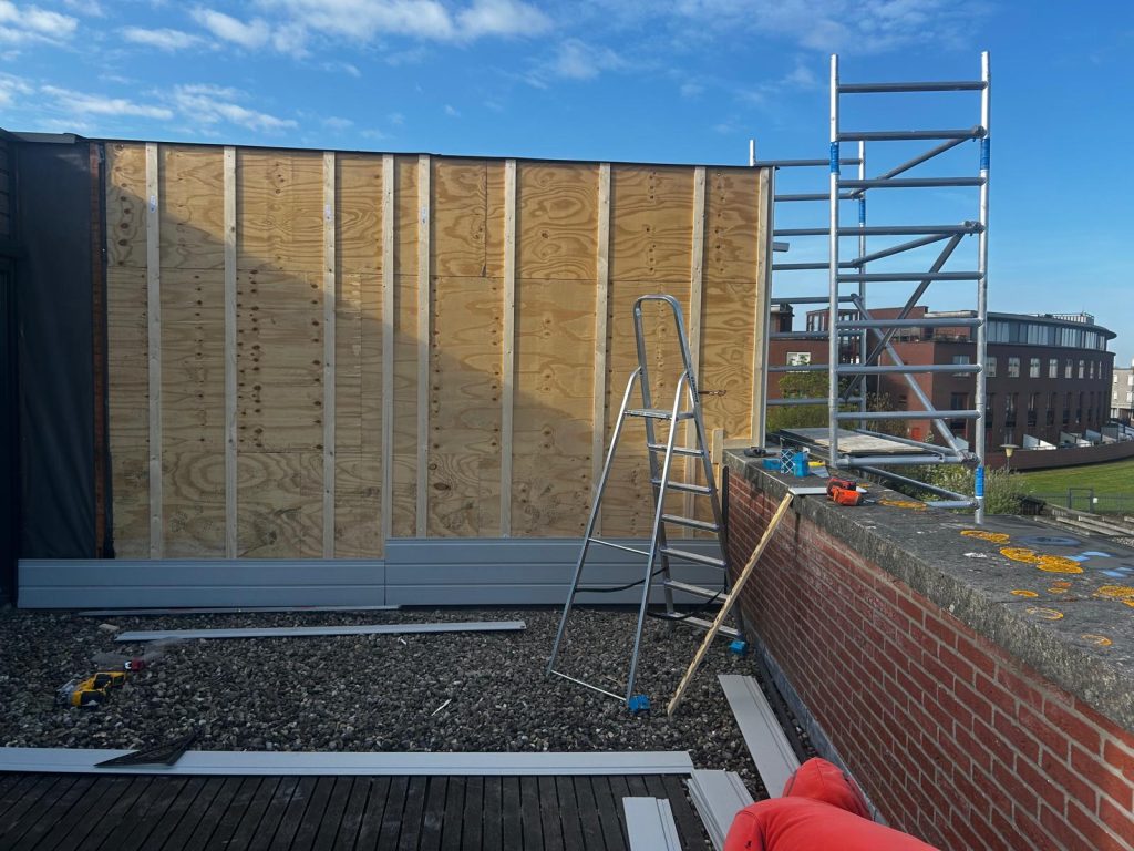 Houten wandconstructie op dak met steiger en ladder