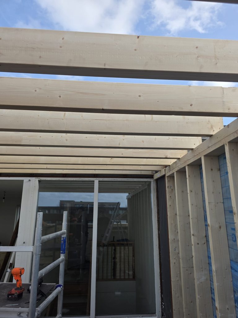 Houten balkenconstructie boven schuifpui in aanbouw