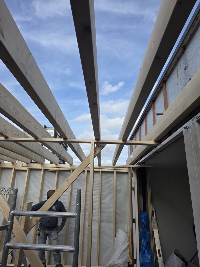 Houten dakconstructie in aanbouw met bouwvakker